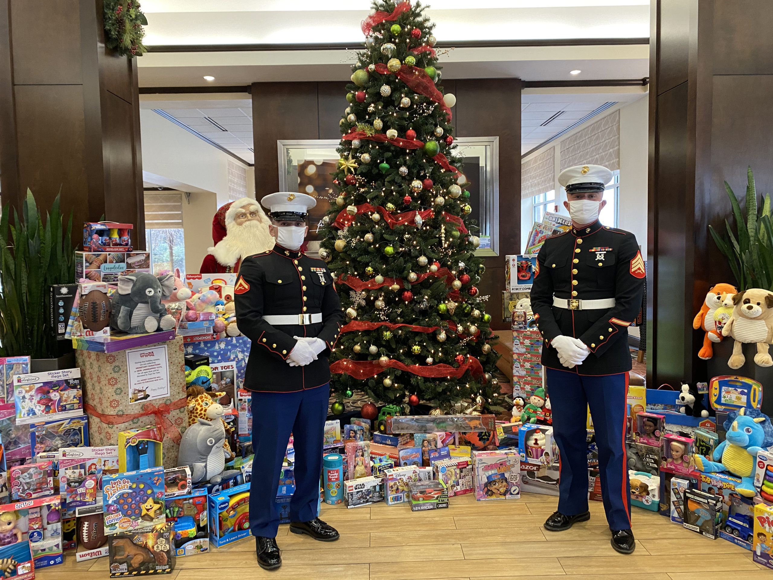 Marines in uniform standing in front of Christmas tree and gifts