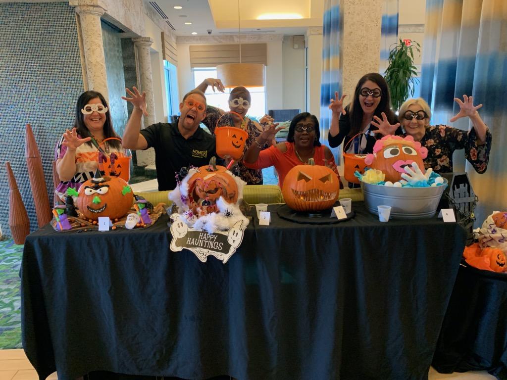 People in front of decorated pumpkins wearing spooky glasses