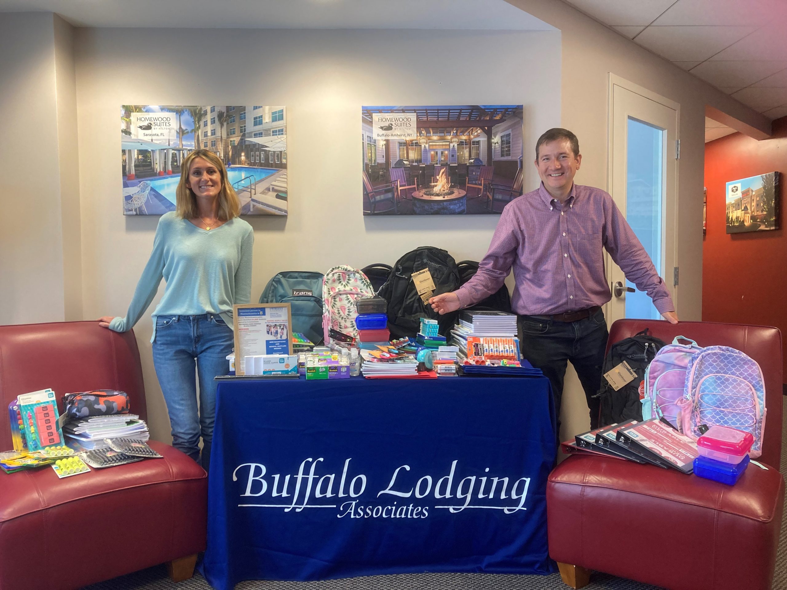 Two Buffalo Lodging employees standing in front of school supply donations