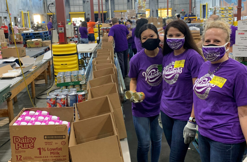 Employees volunteering at a food pantry putting cans of food in boxes